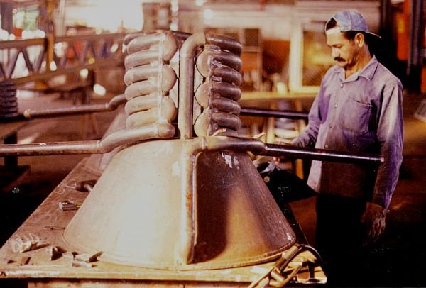 Trabajador junto a una pieza de metal en una fotografía histórica del taller