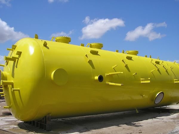 Recipiente cilíndrico industrial amarillo con conexiones y aberturas exteriores
